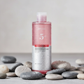 Anua Brightening Toner on wet river pebbles
