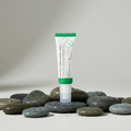 AXIS-Y Dark Spot Correcting Glow Serum on wet river pebbles